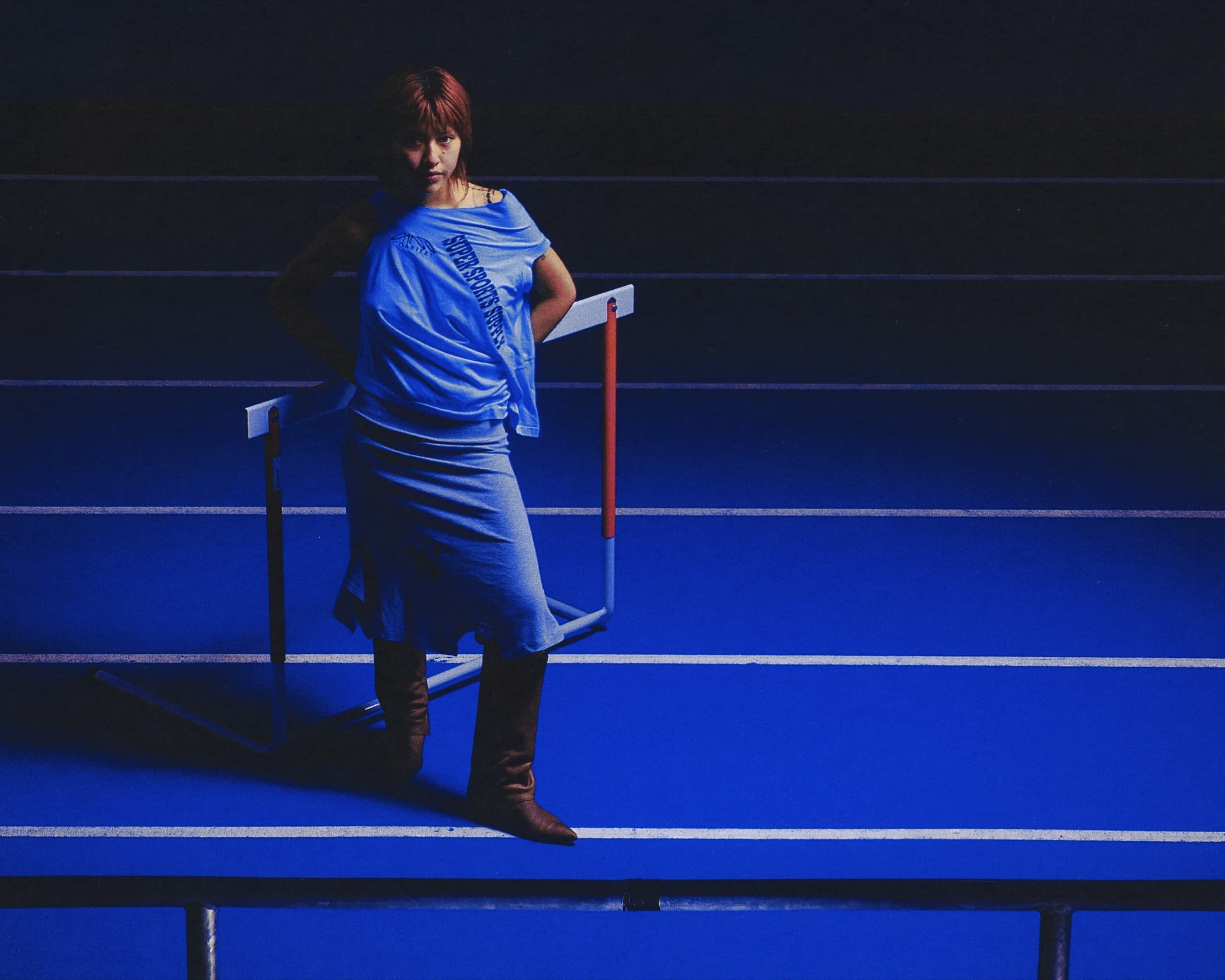 Gina Corrieri SS24 editorial, blue track, standing pose. Photo by George William Vicary.