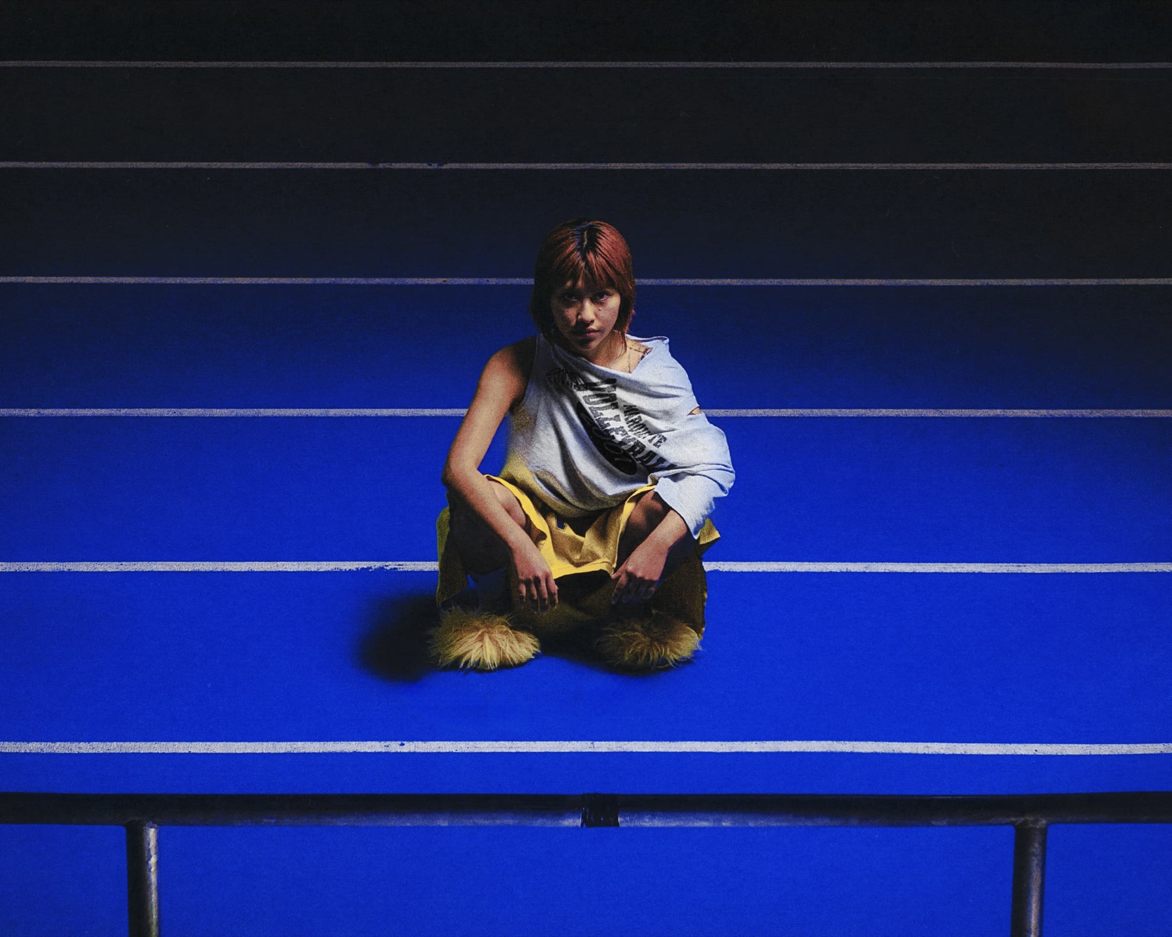 Gina Corrieri SS24 editorial, blue track, seated pose. Photo by George William Vicary.
