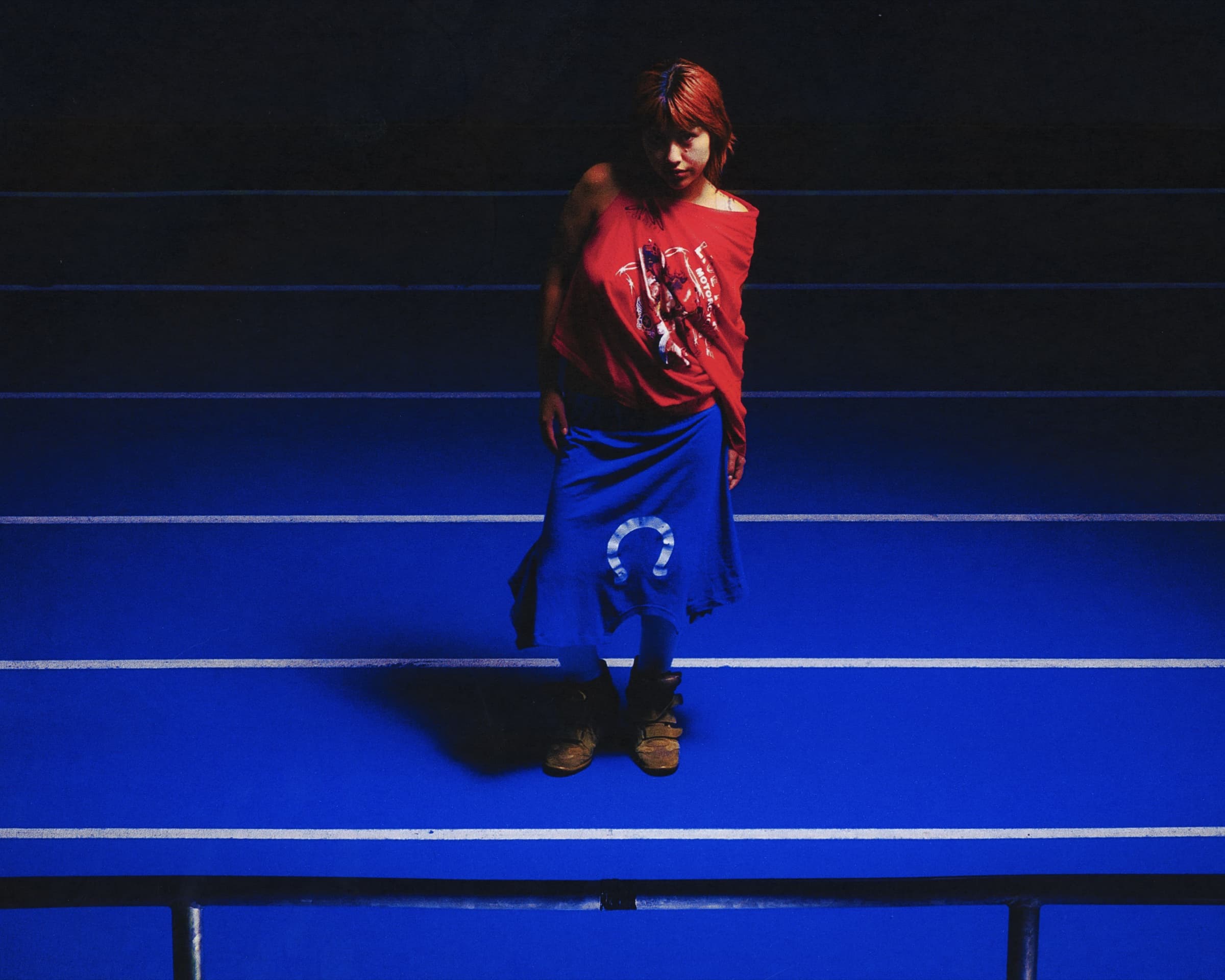 Gina Corrieri SS24 editorial, blue track, red top standing. Photo by George William Vicary.
