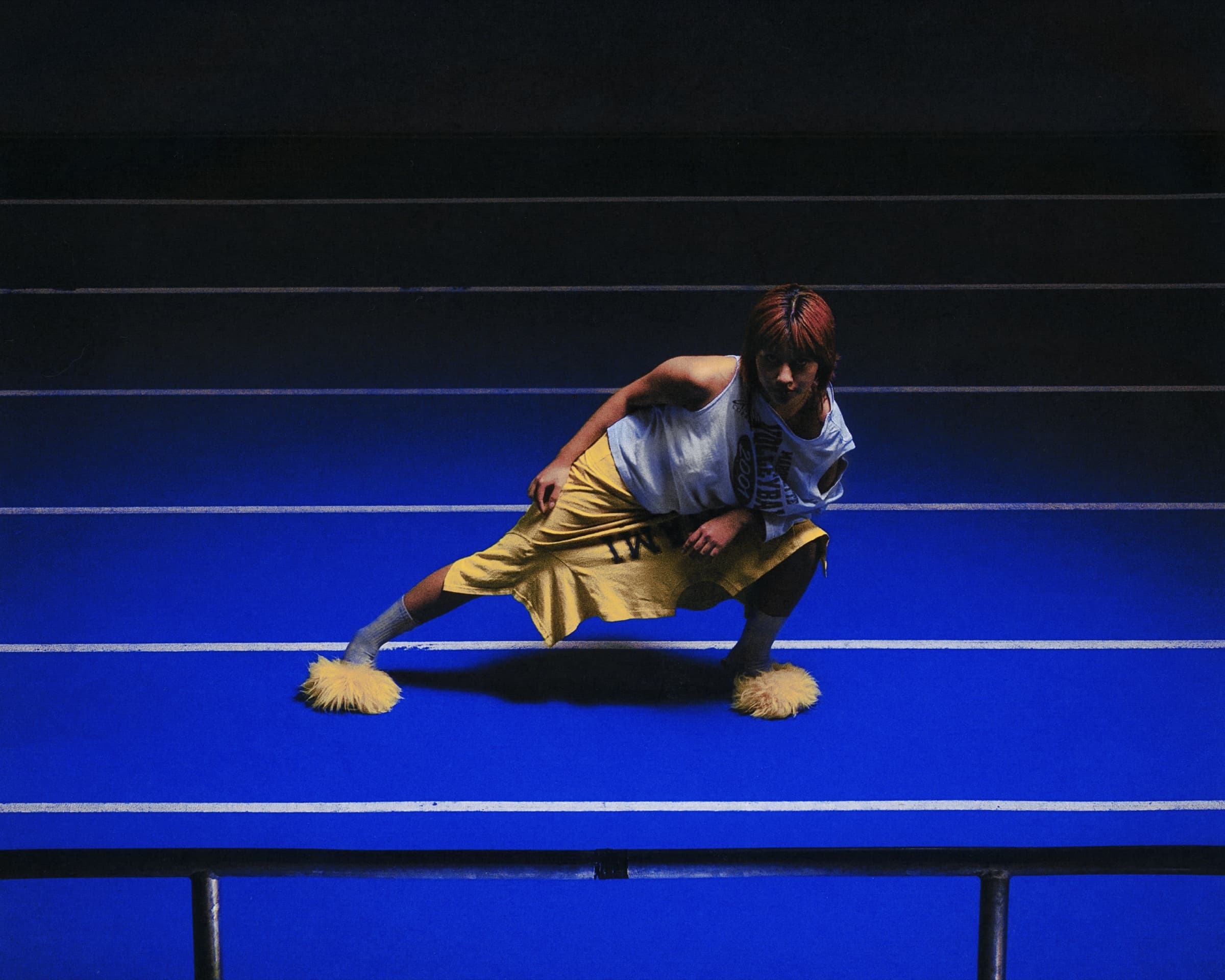 Gina Corrieri SS24 editorial, blue track, crouch pose. Photo by George William Vicary.