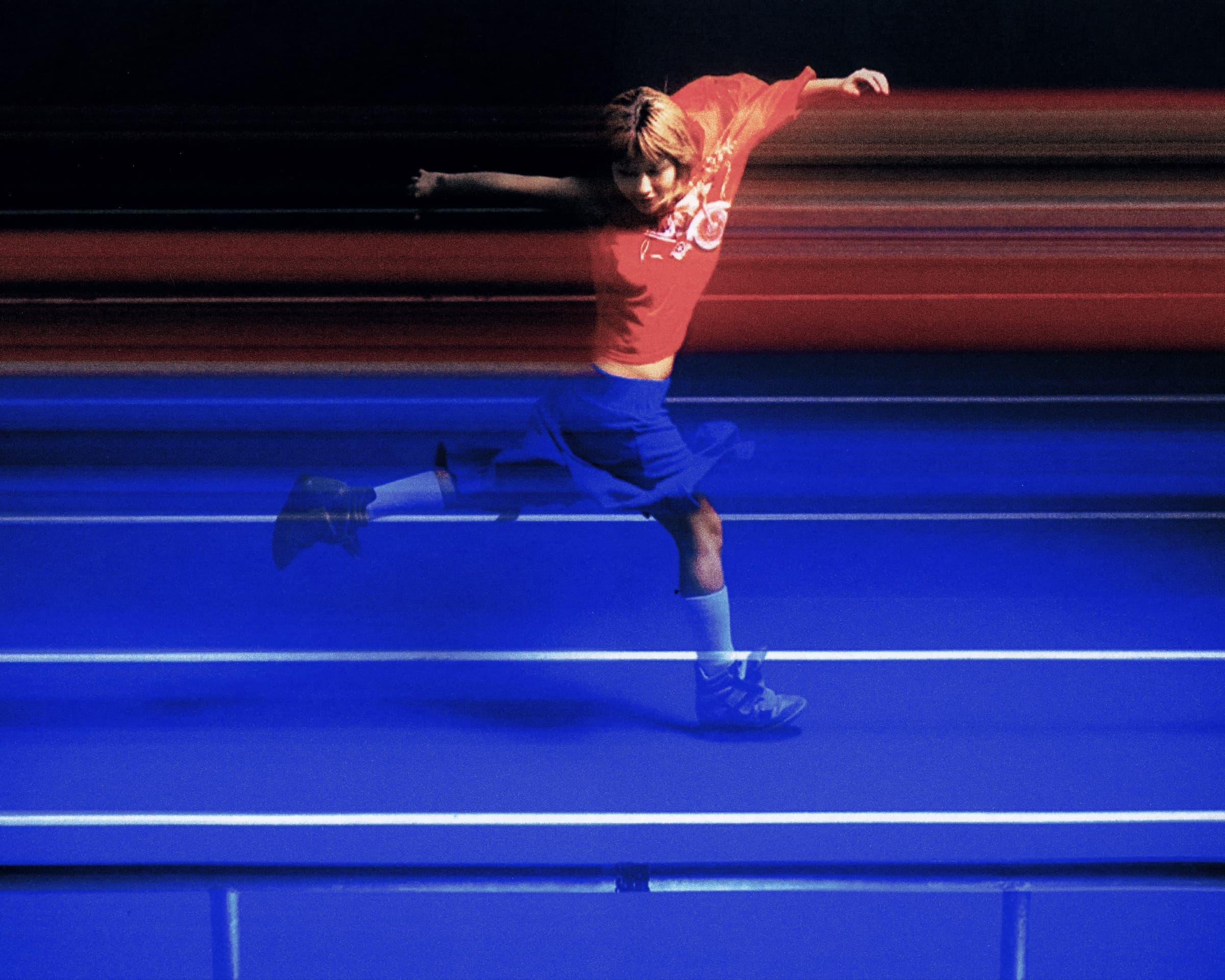Gina Corrieri SS24 editorial, blue track, mid-leap motion frame. Photo by George William Vicary.