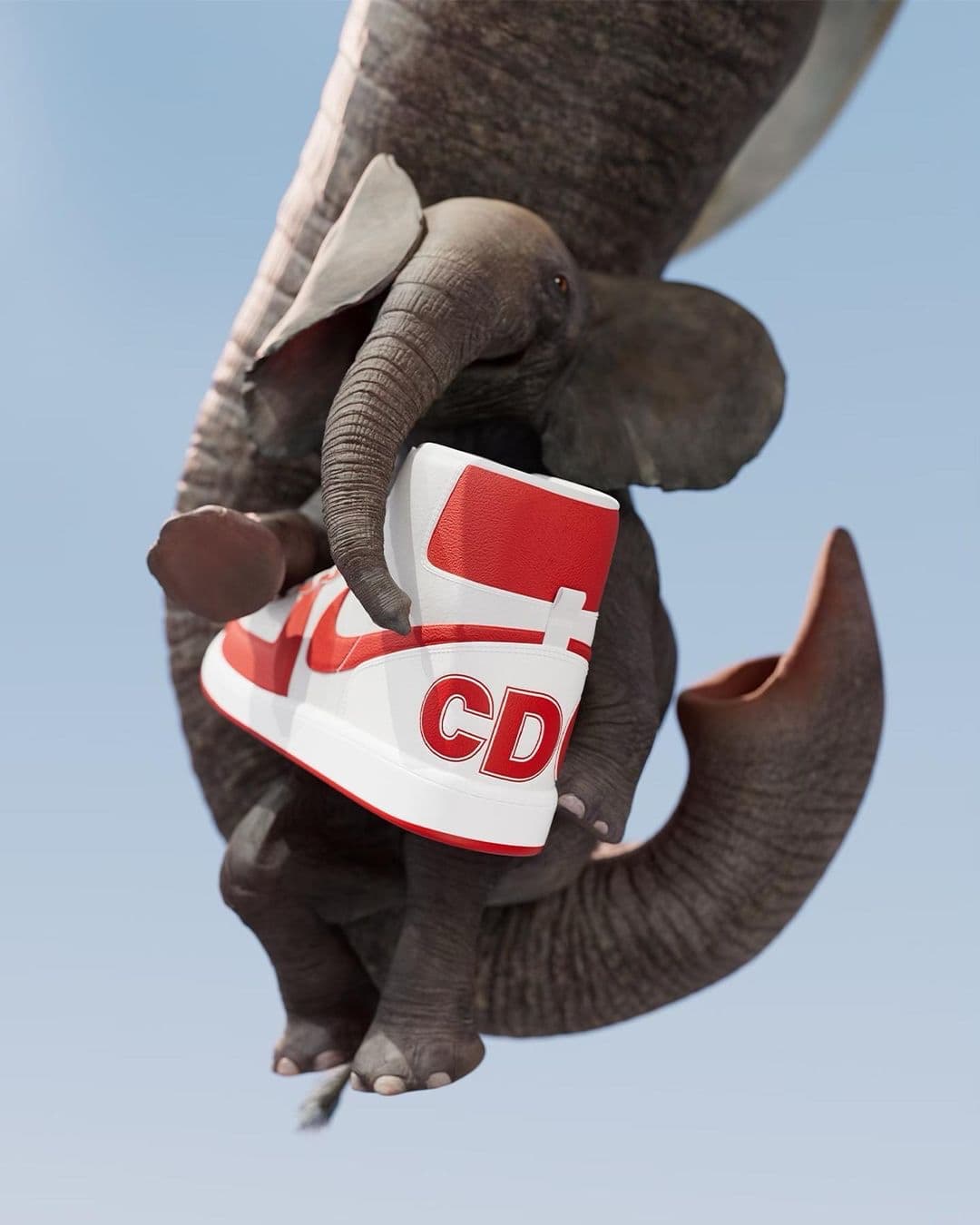 Comme des Garçons x Nike still, an elephant cradling a red-and-white Nike Terminator against the sky.
