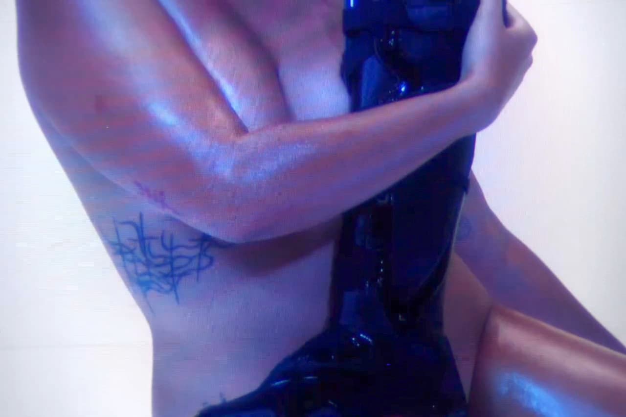 Ottolinger x Puma still, a figure lit in blue holding a glossy black piece.